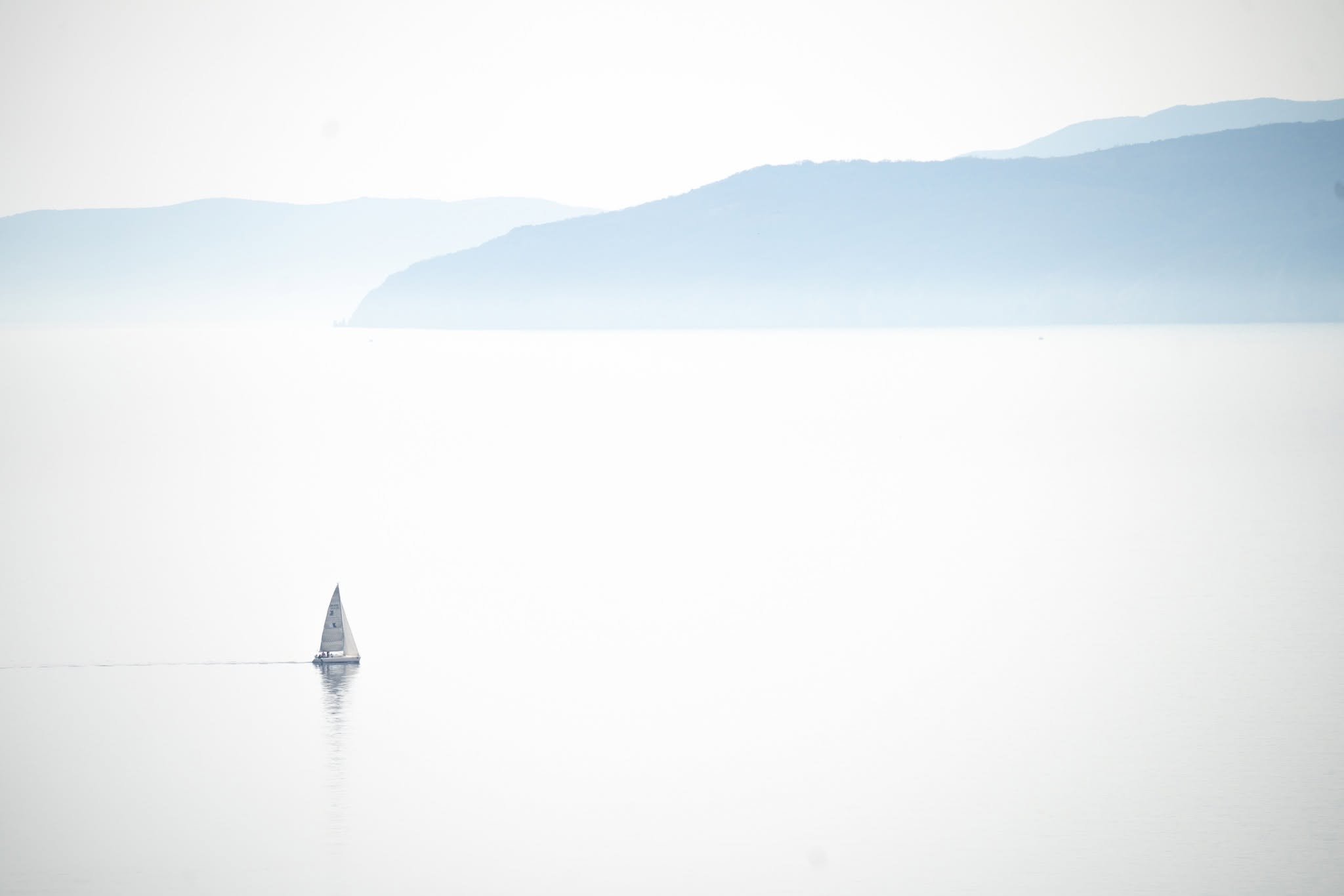 Minimal sailboat on a pale sea