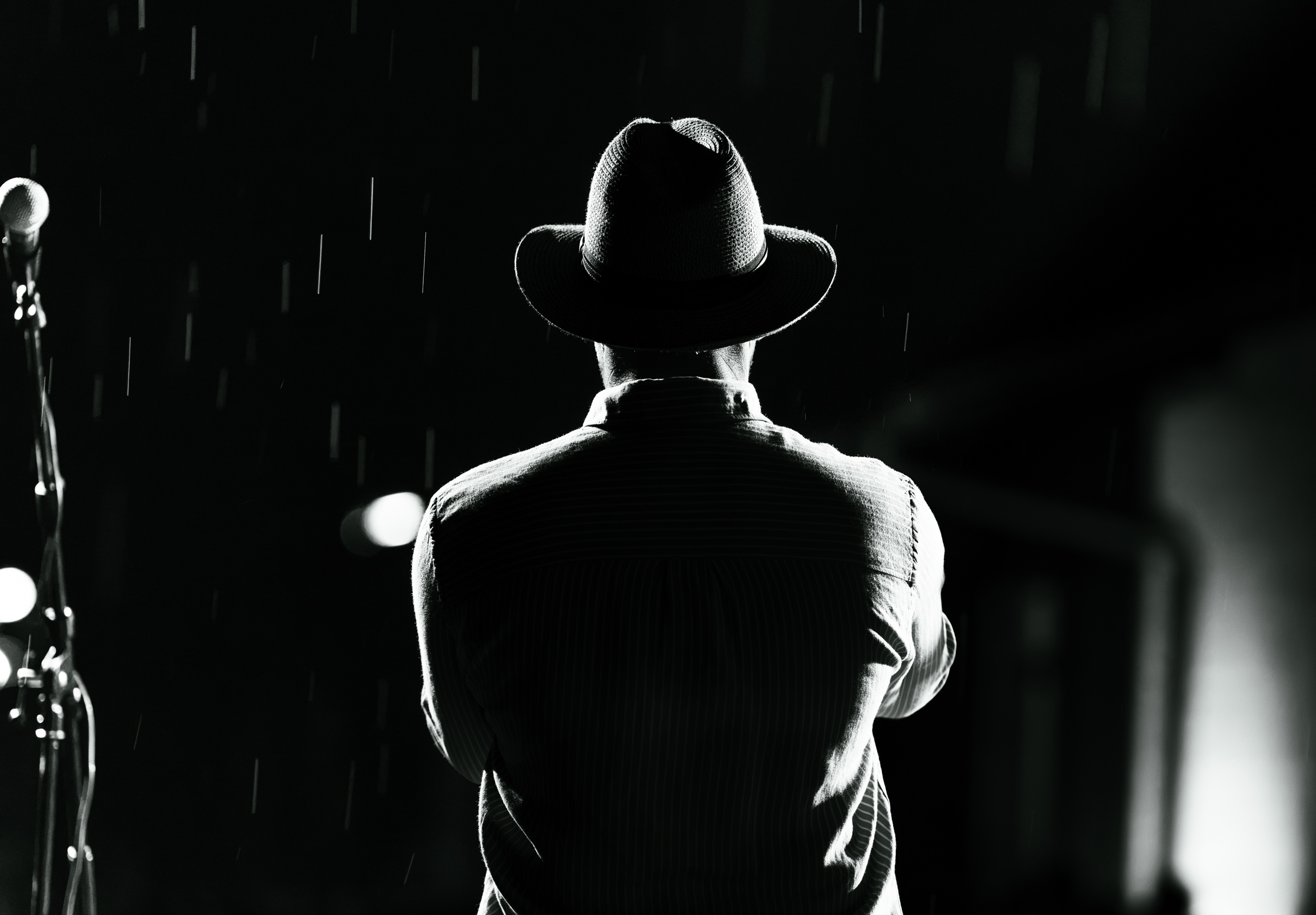 Black and white horn player in the rain with back to camera